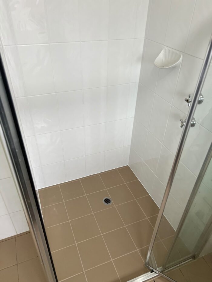 The same shower floor after MRX regrouting, with clean grout lines and fresh silicone