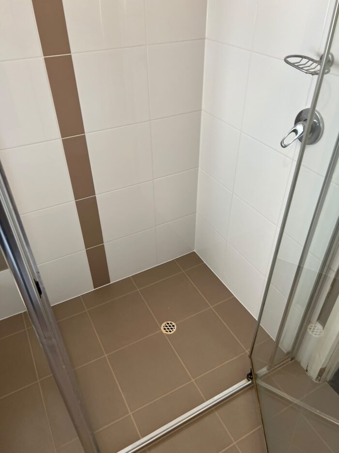Shower base after MRX repair, with solid new grout joints and a sealed perimeter