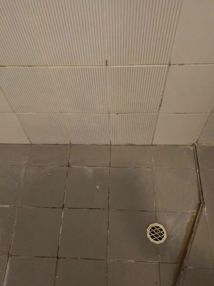 Shower recess before restoration, with stained grout and perished silicone in the corners